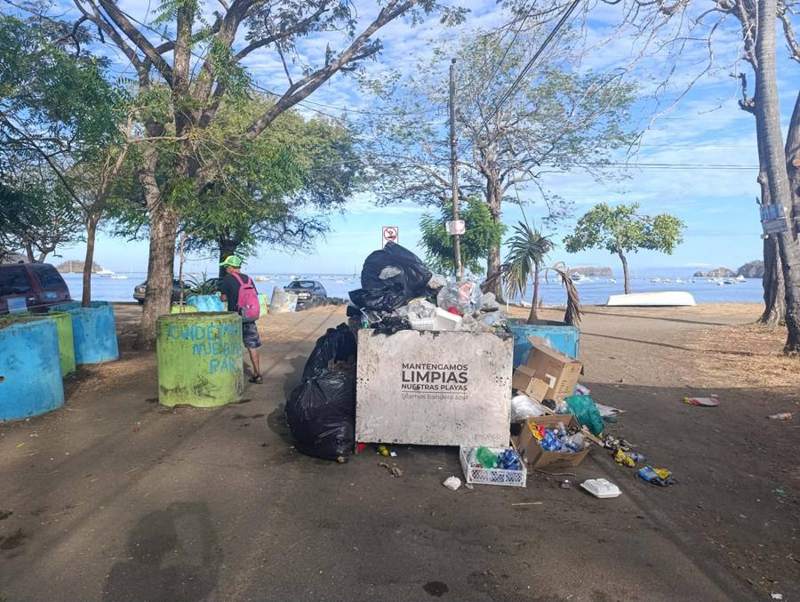 Litter piled around a bin on the beach.